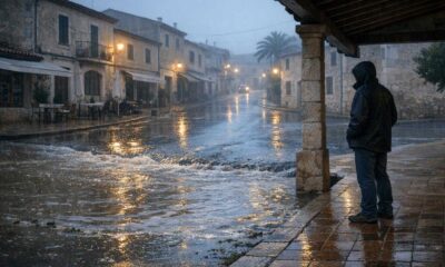 Regennasse Straße auf Mallorca mit einer überfluteten Senke und einer Person in sicherem Abstand.