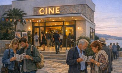 Besucher betrachten vor einem Kino auf Mallorca das Festivalprogramm.
